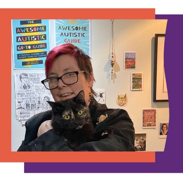 A person holding a black cat in front of a wall decorated in “The Awesome Autistic Guide posters”.