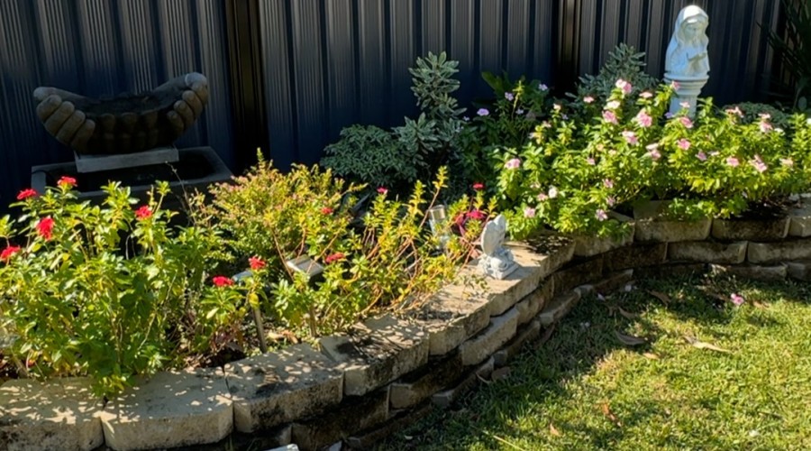 The DAIWS Memorial Garden, featuring flowering plants, decorative garden elements, and a water feature.