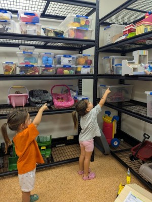 Mimi's children point up at a toy on the shelf in their local toy library.